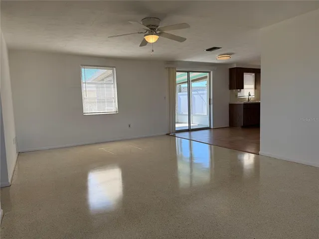 an empty room with windows and chandelier fan