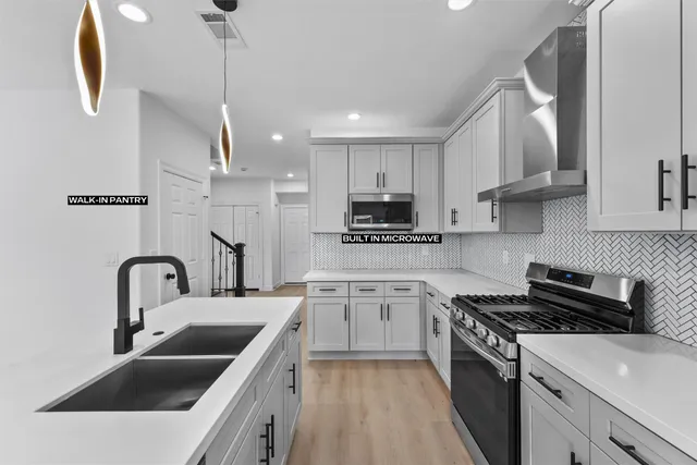 a kitchen with stainless steel appliances a sink a stove a microwave a sink a refrigerator and cabinets