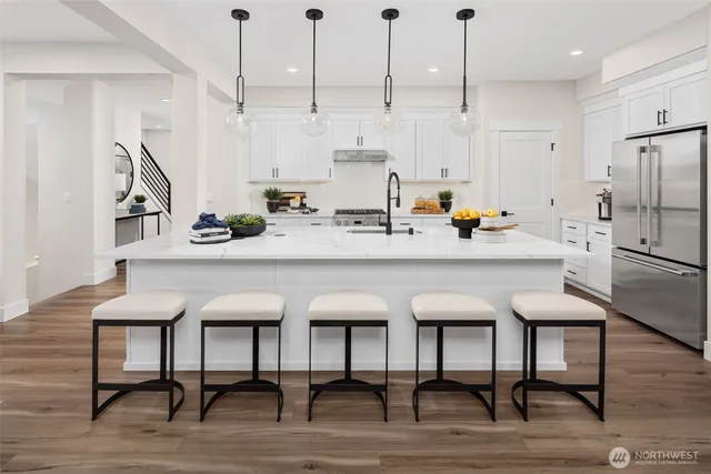 a kitchen with stainless steel appliances kitchen island a table chairs in it and wooden floors