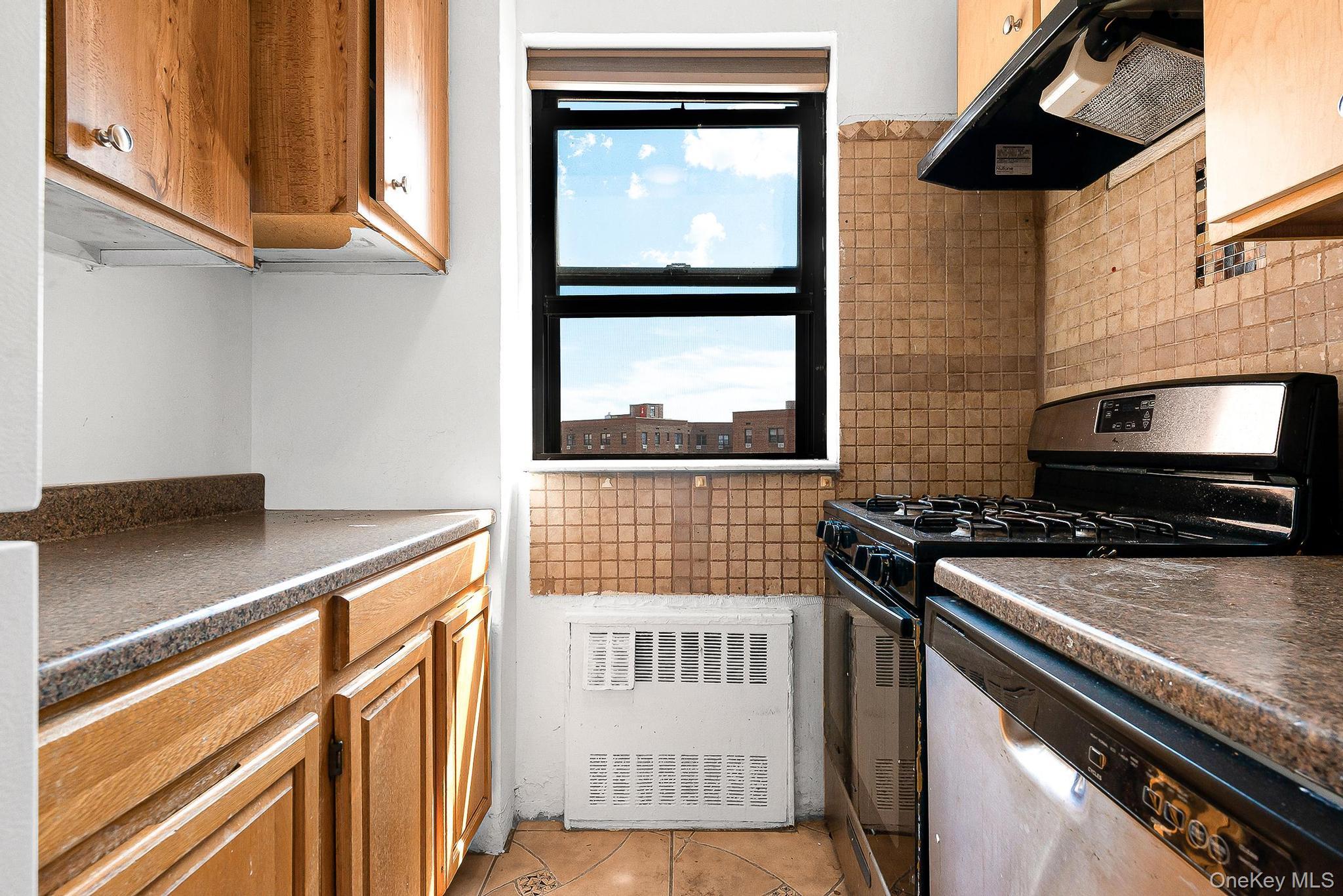 99-32 66th Road, Unit 5B Queens, NY 11374 - Photo 8 of 27 Kitchen with stainless steel appliances, extractor fan, tasteful backsplash, dark countertops, and light tile patterned floors