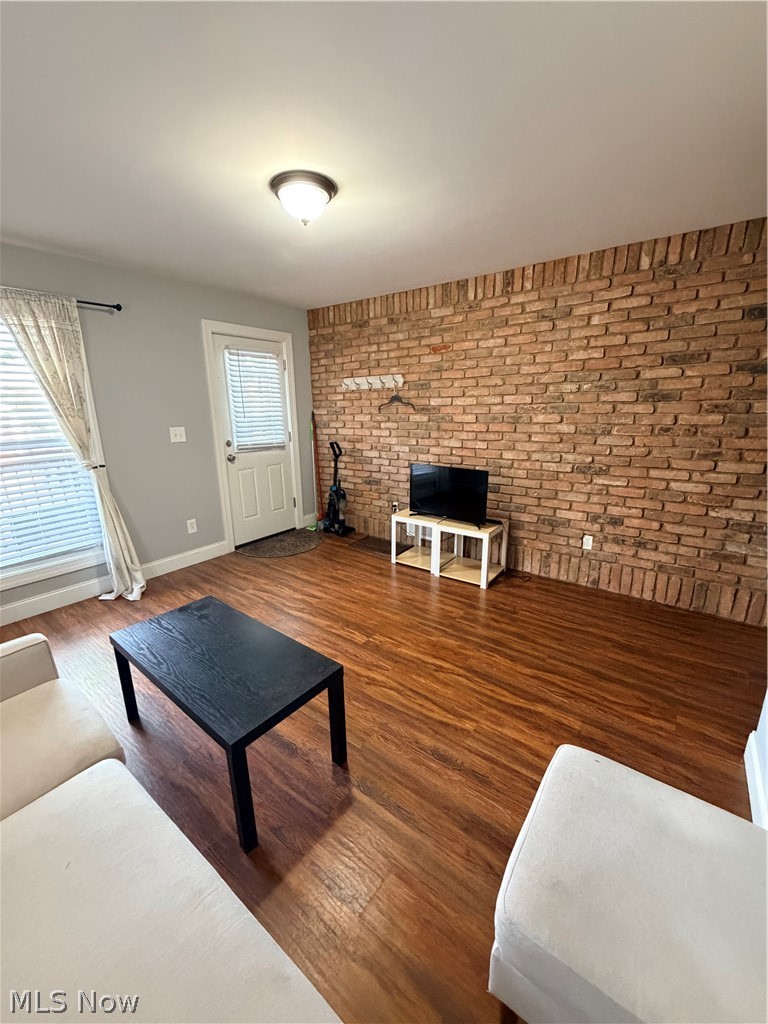 Wood-finish flooring with a brick accent wall, white door with integrated blinds, and recessed ceiling lighting
