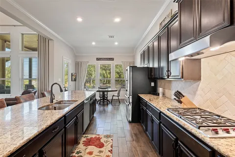 a open kitchen with stainless steel appliances granite countertop a stove top oven a sink dishwasher and dining table with wooden floor