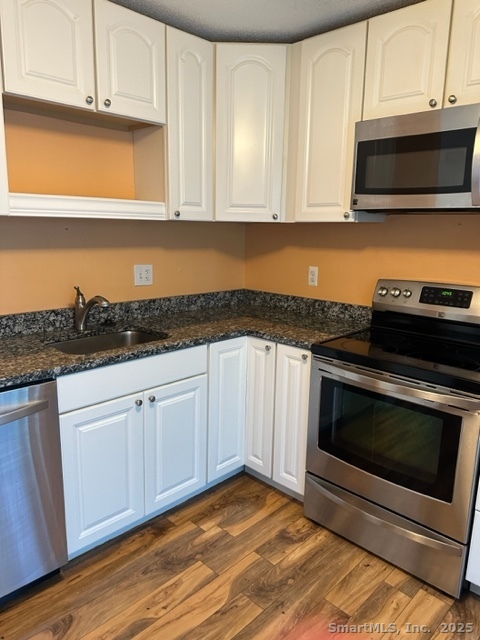 a kitchen with granite countertop cabinets stainless steel appliances and wooden floor