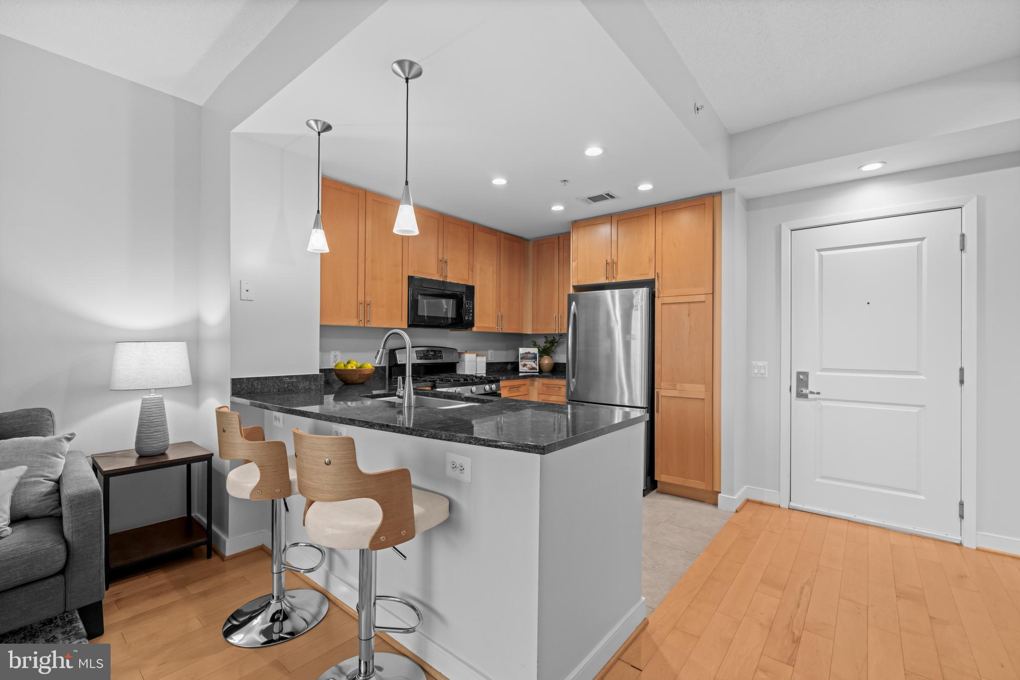 820 North Pollard Street, Unit 307 Arlington, VA 22203 - Photo 12 of 29 a kitchen with stainless steel appliances granite countertop a refrigerator a stove a sink a dining table and chairs with wooden floor