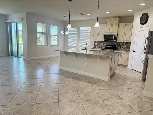 a large kitchen with granite countertop a stove a sink and a refrigerator