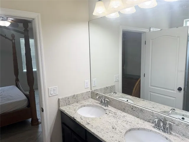 a en suite bathroom with a granite countertop sink and a mirror