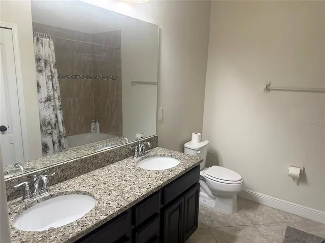 a bathroom with a granite countertop sink a toilet a mirror and shower
