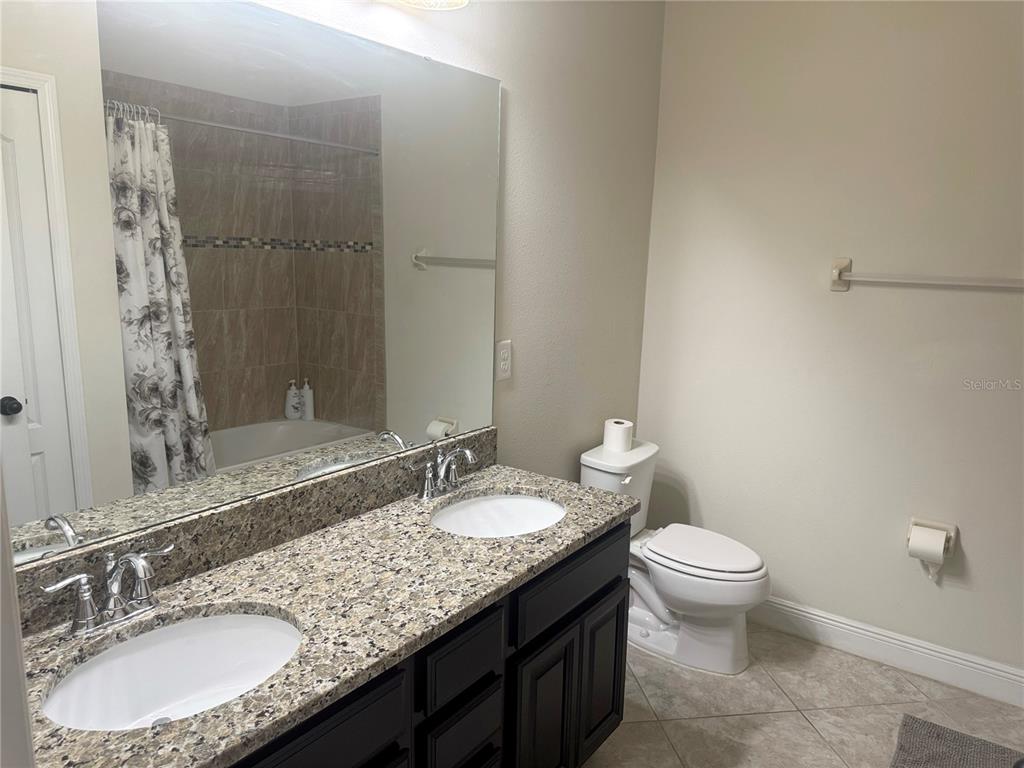 5082 Inshore Landing Drive Apollo Beach, FL 33572 - Photo 29 of 48 a bathroom with a granite countertop sink a toilet a mirror and shower