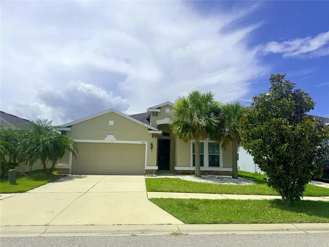 a front view of a house with a garden and trees