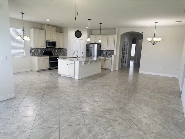 a large kitchen with stainless steel appliances kitchen island granite countertop a stove top oven a sink a counter top space and cabinets