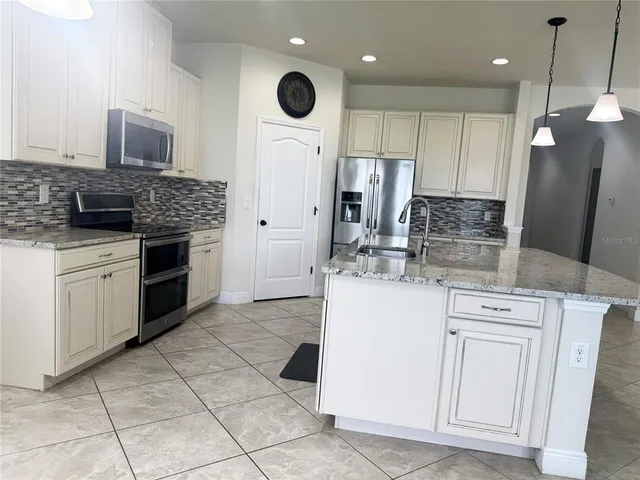 a kitchen with kitchen island granite countertop a stove a sink and a refrigerator with wooden floor