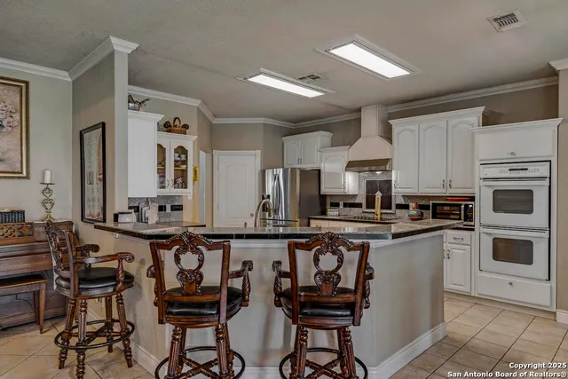 a kitchen with stainless steel appliances granite countertop a stove top oven a sink a dining table and chairs