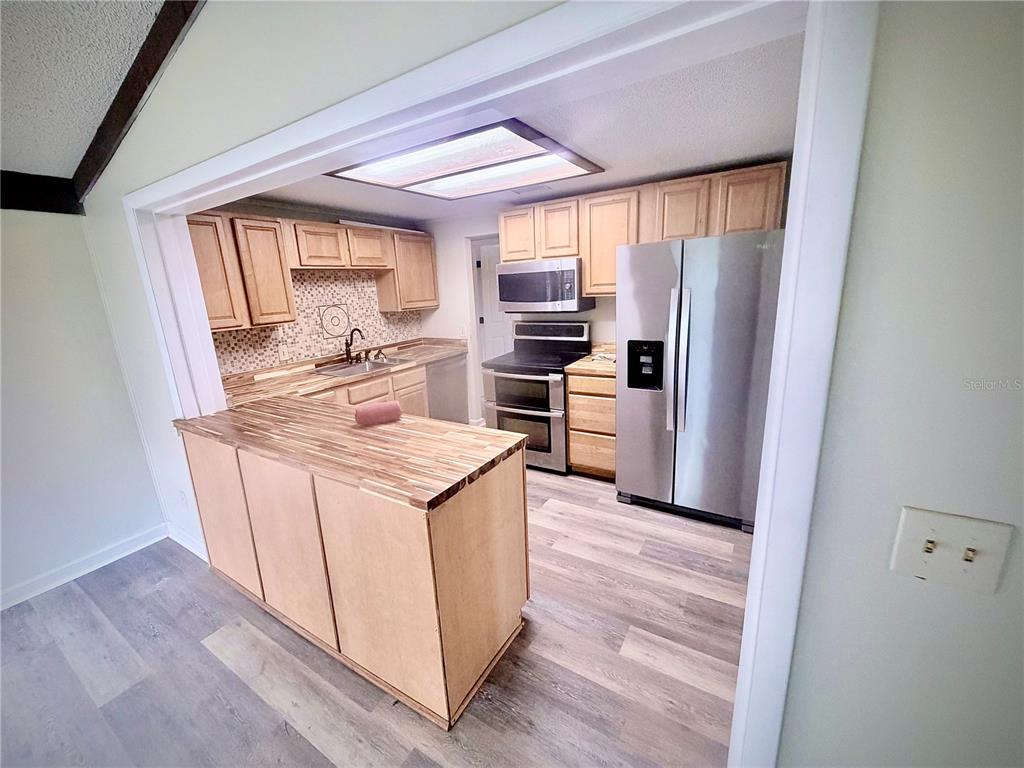 375 Pine Woods Road Ormond Beach, FL 32174 - Photo 7 of 16 a view of a kitchen with wooden floor and electronic appliances