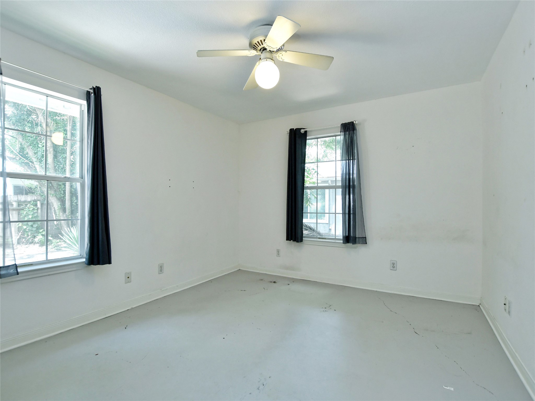 4604 Red River Street, Unit A Austin, TX 78751 - Photo 11 of 15 Interior room featuring two windows, a ceiling fan with light fixture, and light-colored flooring
