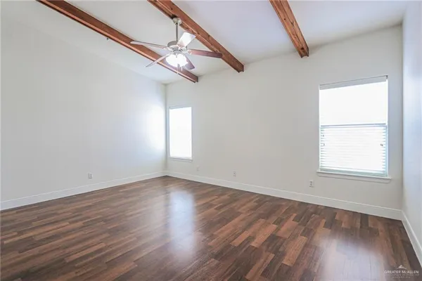 an empty room with wooden floor fan and windows