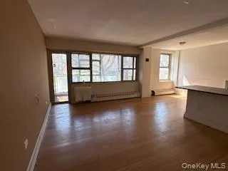an empty room with wooden floor and windows with curtains