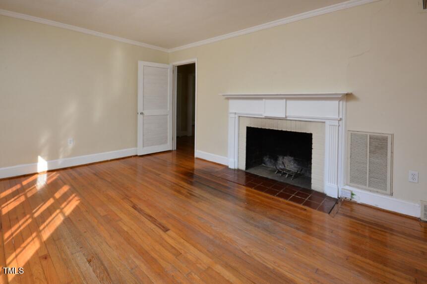 1817 Hillcrest Drive Durham, NC 27705 - Photo 8 of 29 a view of an empty room with wooden floor fireplace and a window