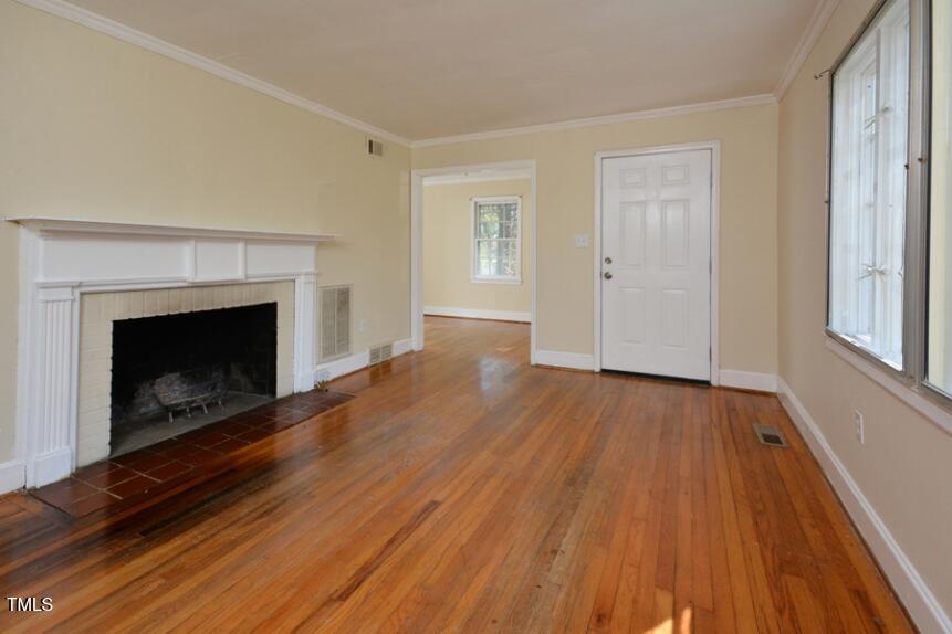 1817 Hillcrest Drive Durham, NC 27705 - Photo 9 of 29 a view of empty room with wooden floor and fireplace
