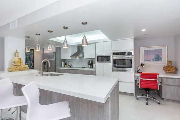 a kitchen with stainless steel appliances kitchen island granite countertop a sink and a white cabinets