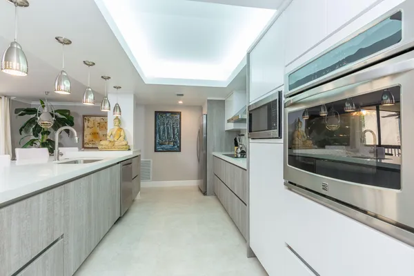 a large white kitchen with a large window and stainless steel appliances