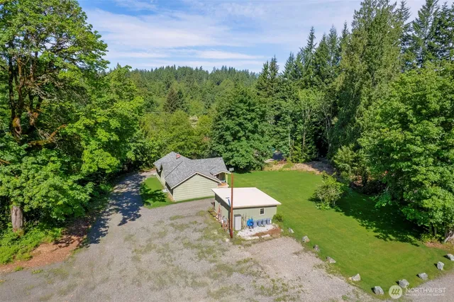 an aerial view of residential house with outdoor space and trees all around