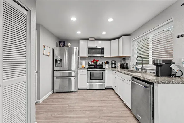 a kitchen with granite countertop a refrigerator and a stove top oven