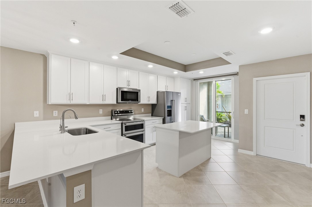 44000 Boardwalk Loop, Unit 1312 Punta Gorda, FL 33982 - Photo 17 of 48 a kitchen with stainless steel appliances a stove a sink a microwave a refrigerator a stove and white cabinets with wooden floor