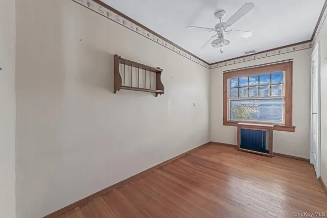 a view of an empty room with a window and wooden floor