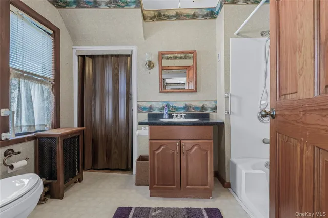 a bathroom with a granite countertop sink a toilet a mirror and shower