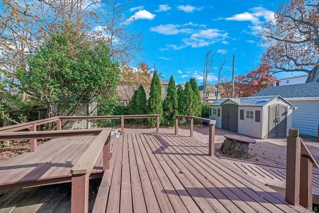 a view of a roof deck with table and chairs a barbeque with wooden floor and fence