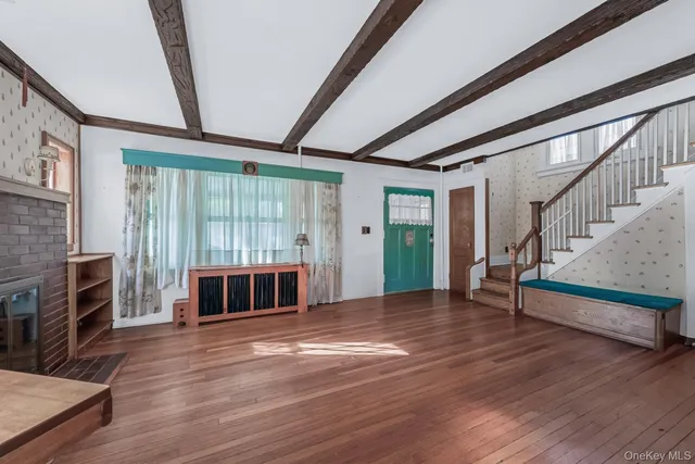 a view of an empty room with wooden floor fireplace and a window