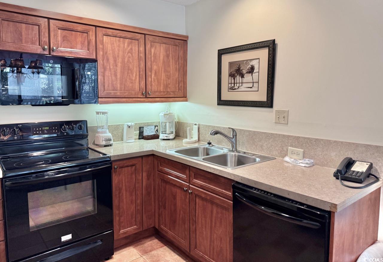 404 Melrose Place, Unit 21A Myrtle Beach, SC 29572 - Photo 14 of 30 Kitchen with black appliances, light countertops, brown cabinetry, and light tile patterned floors
