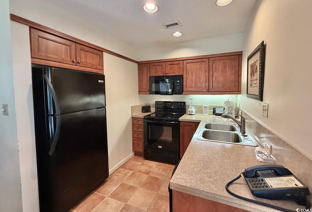 404 Melrose Place, Unit 21A Myrtle Beach, SC 29572 - Photo 15 of 30 Kitchen featuring light countertops, black appliances, brown cabinetry, recessed lighting, and a textured ceiling