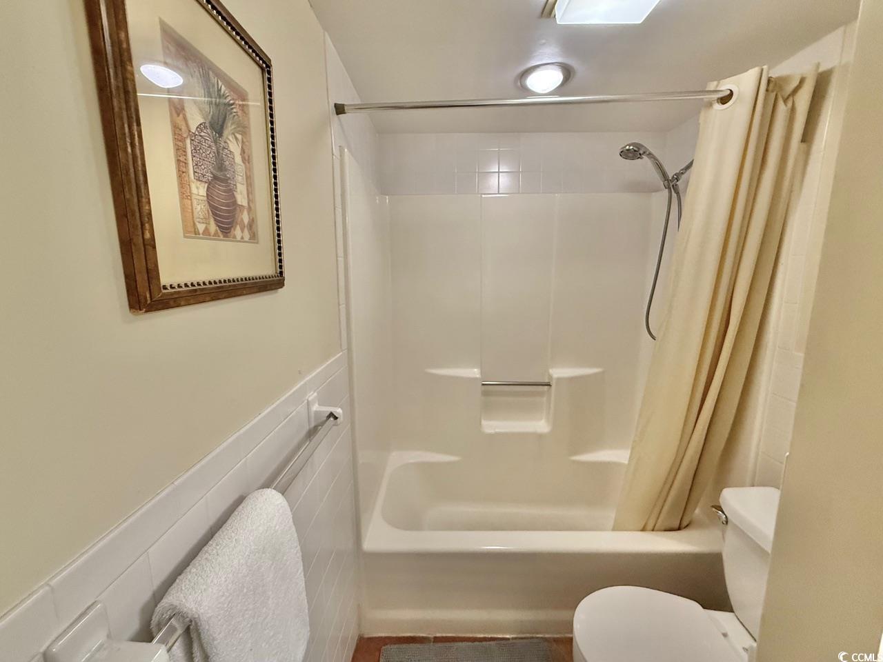 404 Melrose Place, Unit 21A Myrtle Beach, SC 29572 - Photo 21 of 30 Bathroom with shower / bath combo with shower curtain and a wainscoted wall
