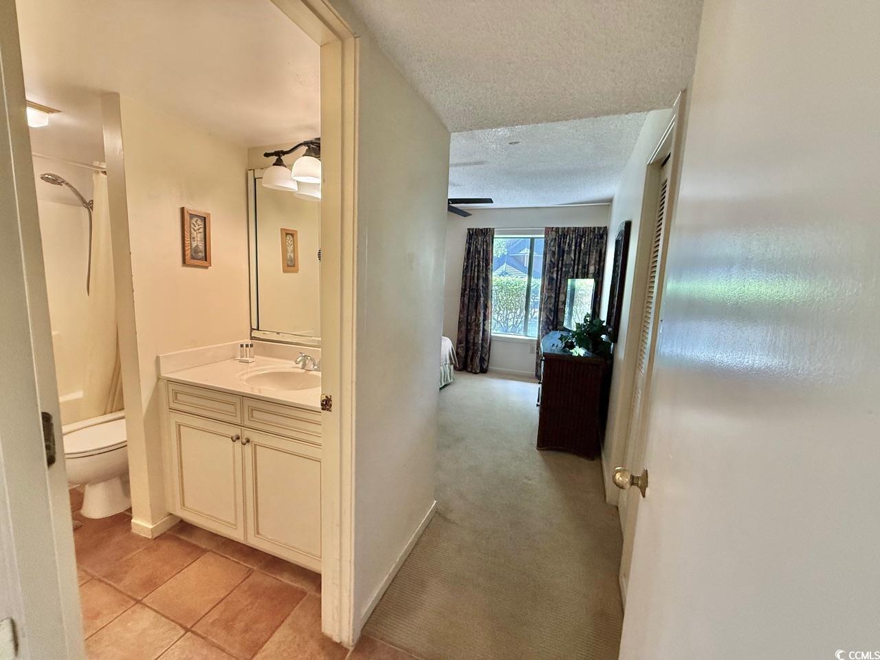 404 Melrose Place, Unit 21A Myrtle Beach, SC 29572 - Photo 24 of 30 Bathroom featuring a textured ceiling, vanity, light colored carpet, light tile patterned flooring, and shower / tub combo with curtain