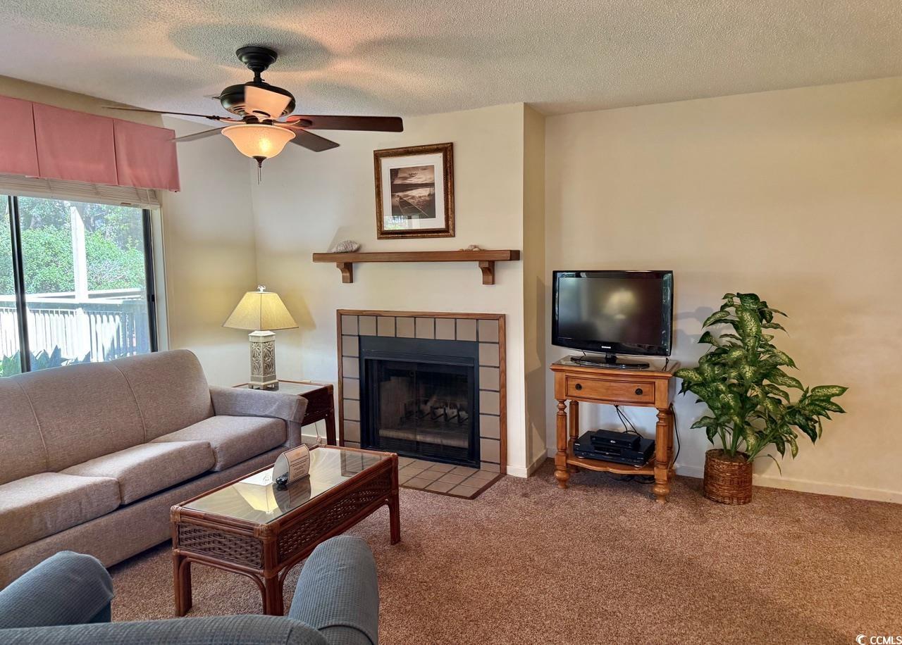 404 Melrose Place, Unit 21A Myrtle Beach, SC 29572 - Photo 6 of 30 Living area featuring carpet, a tiled fireplace, a textured ceiling, and ceiling fan