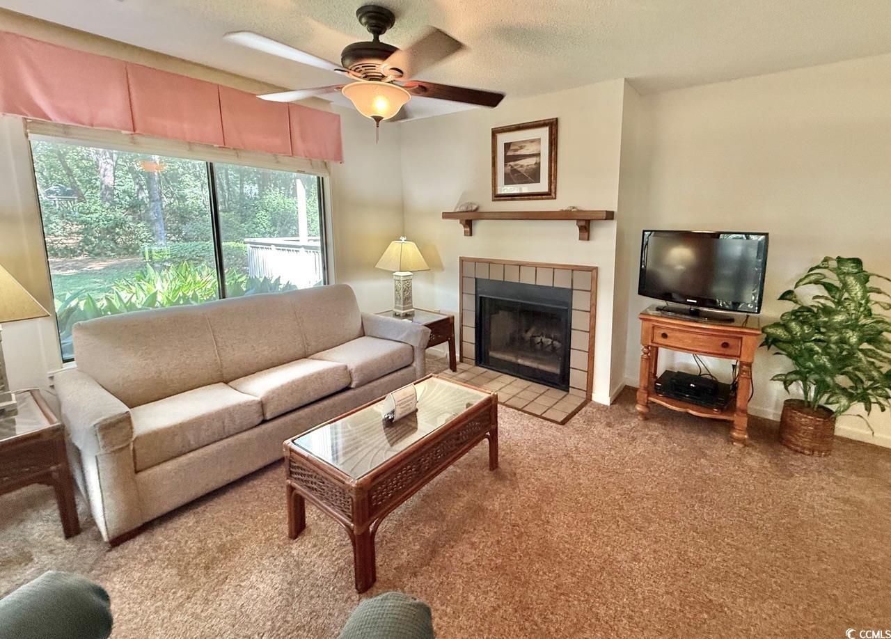404 Melrose Place, Unit 21A Myrtle Beach, SC 29572 - Photo 7 of 30 Carpeted living room with a tiled fireplace, a textured ceiling, and a ceiling fan