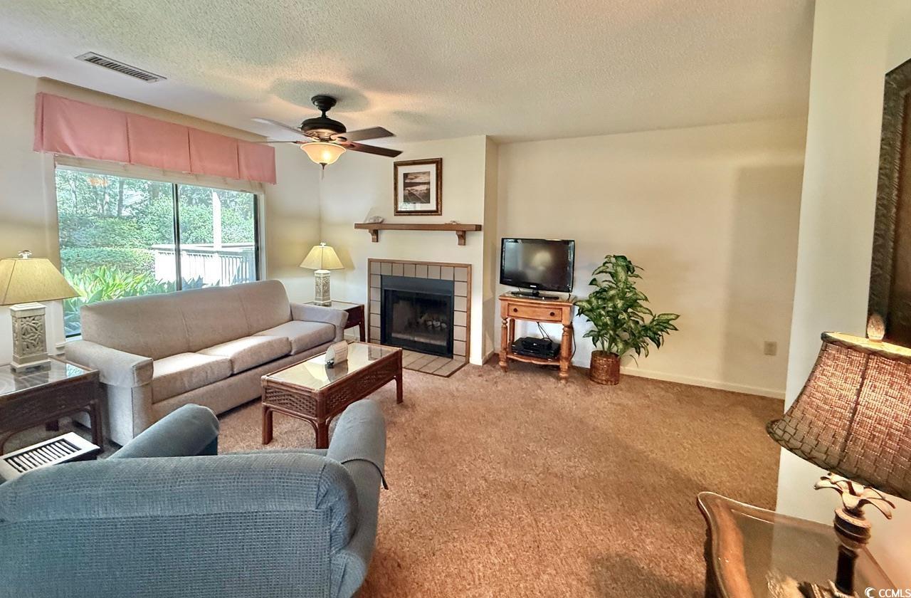 404 Melrose Place, Unit 21A Myrtle Beach, SC 29572 - Photo 8 of 30 Living room with a tile fireplace, a textured ceiling, carpet floors, and a ceiling fan