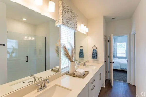 a bathroom with a double vanity sink mirror and shower