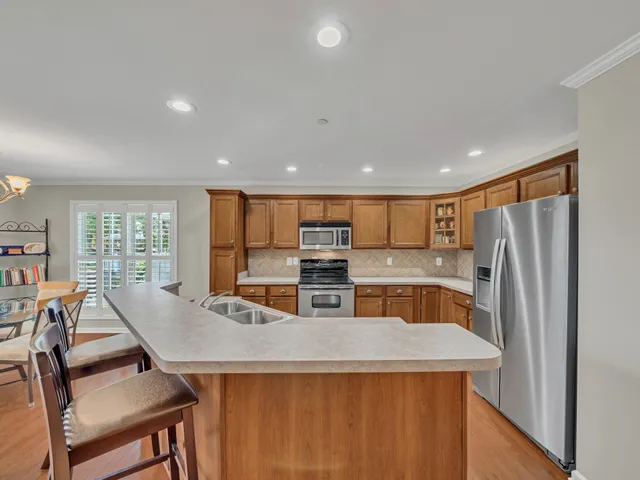 a kitchen with stainless steel appliances a dining table chairs and a refrigerator