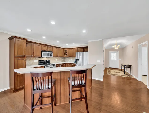 a kitchen with stainless steel appliances kitchen island granite countertop a dining table chairs and a refrigerator