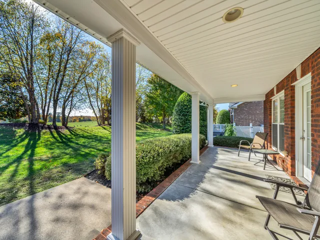 a view of a patio with table and chairs potted plants and large tree