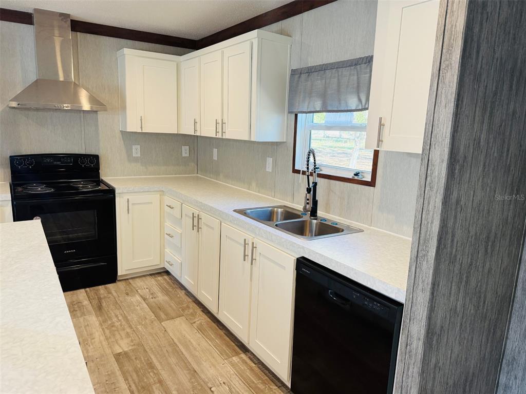 16226 41st Place Wellborn, FL 32094 - Photo 8 of 18 a kitchen with a sink dishwasher a stove and a refrigerator with wooden floor