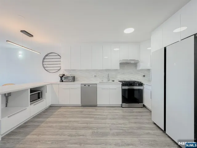 a large kitchen with a large counter top stainless steel appliances and cabinets