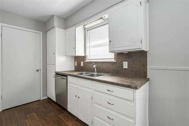 a kitchen with granite countertop white cabinets and sink