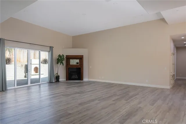 a view of an empty room with window and wooden floor