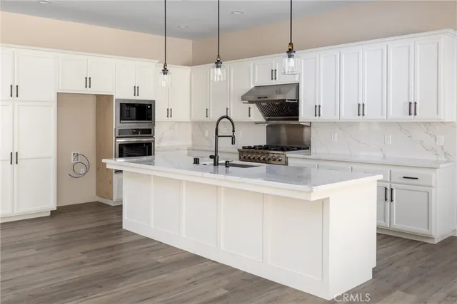 a kitchen with stainless steel appliances white cabinets a sink a stove a refrigerator and microwave