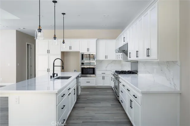 a kitchen with stainless steel appliances granite countertop a sink a stove and a refrigerator