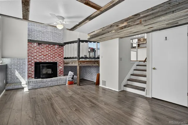 an empty room with wooden floor fireplace and windows