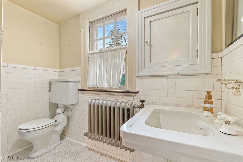 245 Merriman Road Akron, OH 44303 - Photo 28 of 49 Half bathroom with toilet, tile walls, wainscoting, radiator heating unit, and tile patterned flooring